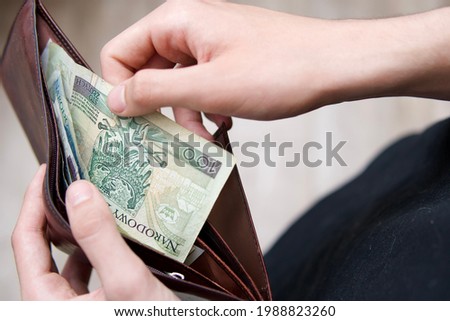 the man takes Polish zlotys from his wallet. Photo concept for an article on economics. Polish economy. Savings or payments in Polish banknotes of various denominations.
