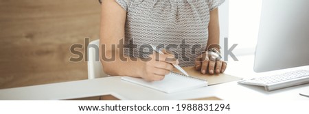 Unknown business woman working with computer while sitting at the desk in modern office, close-up. Middle aged female lawyer or auditor at work