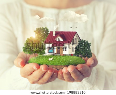 Small fantastic island with a house and backyard in women's hands. Royalty-Free Stock Photo #198883310