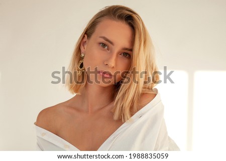 portrait photo of a gentle woman in a white shirt. Photo of a blonde in the sun. A girl with bright makeup, a lot of sparkles on her face. fashion photography. 
beauty shooting
