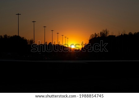 Sunset over the road. Evening on the highway. The sun sets over the horizon. Sunset colors in the atmosphere.
