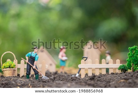 Young farmer uses a rake for grading and amendment soil for farming in front of the fence. Concept of simple living and farming for rural households. macro and blur