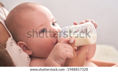 Mom feeds her happy child son baby milk powder, baby bottle Royalty-Free Stock Photo #1988857328
