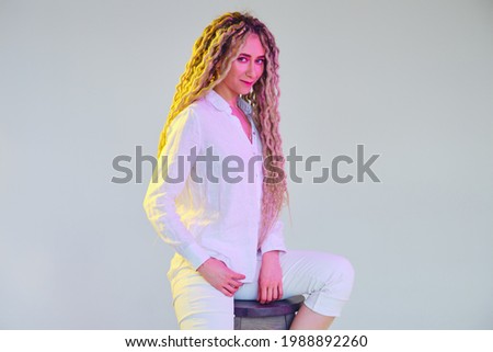Tricky woman in white blouse and trousers under neon light