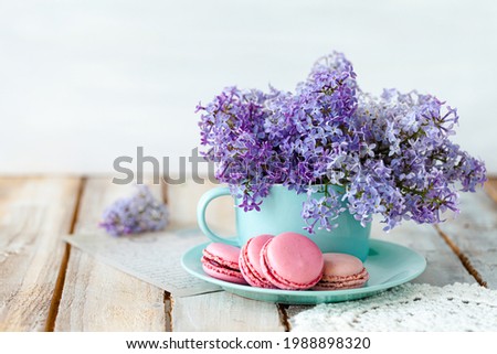 Postcard with violet lilac bouquet in a blue cup and delicious french macarons. Template for birthday card, Mother's Day, Saint Valentine's day, 8 March, Women's Day. White background