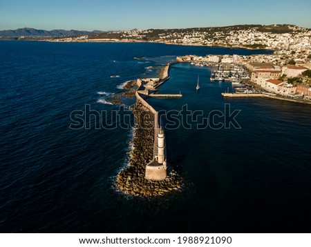 Aerial top view by drone of iconic Venetian lighthouse in the entrance of picturesque old port of Chania at sunset on Crete island, Greece.