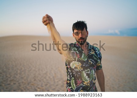 Young man at desert dunes with sand in his hands symbolizing the pass of time
