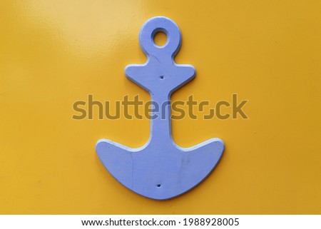 Wooden anchor on yellow background
