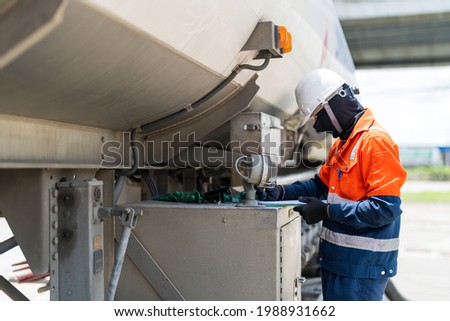 A tanker truck driver delivers gasoline to a gas station