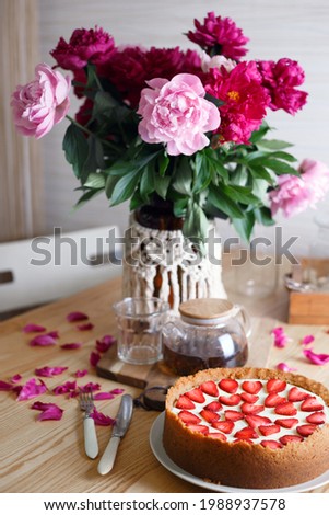 delicious and beautiful breakfast. cheesecake with strawberries on a wooden background with a bouquet of peonies
