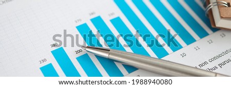 Metal ballpoint pen lying on documents with graphs closeup