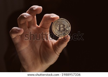 Close up man hand holding golden Bitcoin isolated on black background