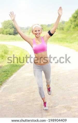 A picture of a joyful woman finishing her run in the park with victory