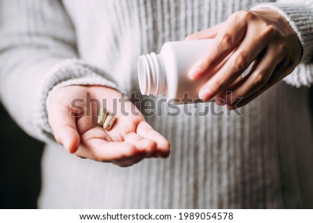 hands young women holding medicine herbs capsules, female taking supplement product or vitamin type capsule, Kariyat or Andrographis herbal. Royalty-Free Stock Photo #1989054578