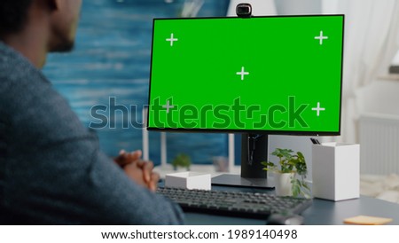 Close up of african american man talking on video call on computer with mock up chroma display, isolated green screen mockup for easy replacement. Computer user on internet online conference call