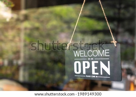"Welcome, open" signboard of the cafe and food restaurant which is display at the entry. The signboard is behind the glass window, cause the lighting reflection from outside environment.
