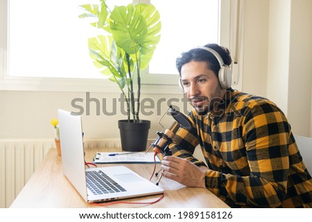 Latino man sitting in a bright office recording a podcast
