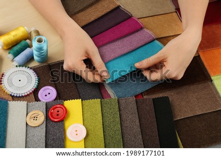 Woman choosing among colorful fabric samples, closeup