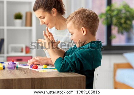 family, creativity and craft concept - mother and little son playing with modeling clay at home