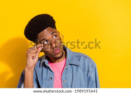 Photo of young minded dark skin man look empty space wear glasses idea isolated on yellow color background