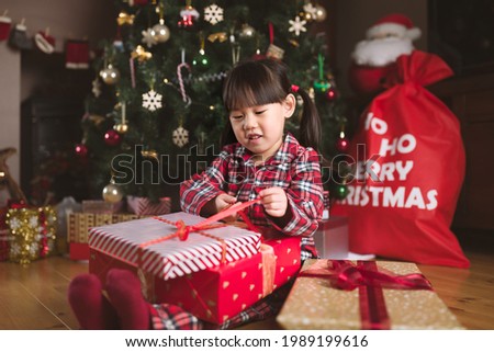 young girl sit on floor and open Christmas gift box at home