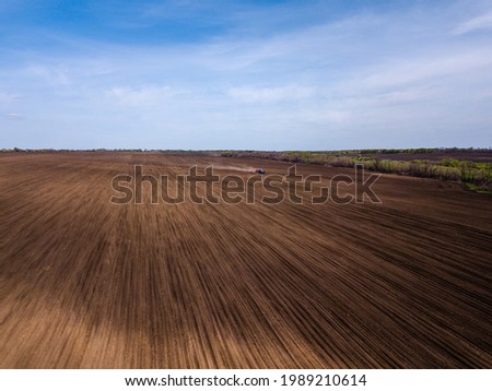 Aerial view of plowing fields by tractor and blue sky