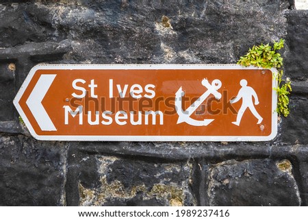 A sign showing visitors the direction of the St. Ives Museum, in the seaside town of St. Ives in Cornwall, UK.