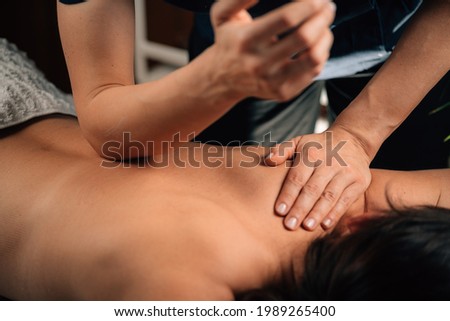 Deep Tissue Massage Therapy. Therapist massaging Woman’s Back, using Elbow Pressure. Royalty-Free Stock Photo #1989265400