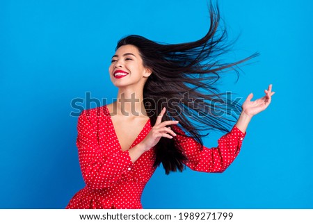 Photo portrait of smiling woman dancing in red dress with flying hair isolated on vivid blue color background