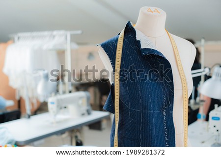 Fashion creative design studio interior concept with mannequin dummy and stylish fashionable trendy clothes on hangers, dressmaking workplace, tailor shop, sewing workshop