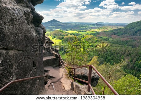 Epic view from Rock of Maria, or Mariina skala, or Marienfels into beautiful landscape of Bohemian Switzerland on a sunny summer day. View from the top of the rock into vast, picturesque landscape. Royalty-Free Stock Photo #1989304958