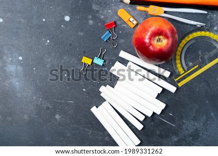 Back to school concept with apple and chalk and school supplies on blackboard background with copy space, top view