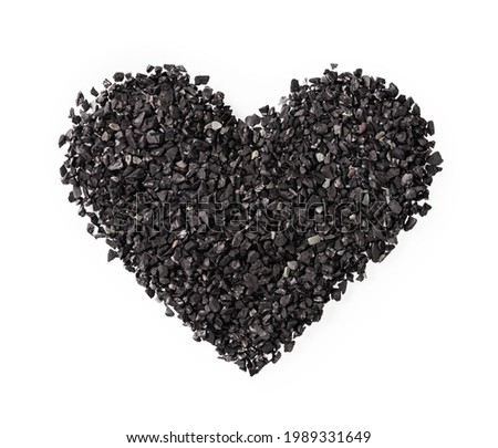 Heart shape of black sand or charcoal isolated on white background. Symbol of love, care and romance for greating card. Dark goth heart sign creative design element. Macro shot. Top view. 