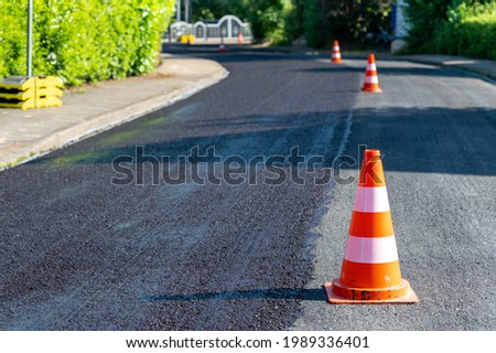 Construction cones marking part of road with a layer of fresh asphalt. 