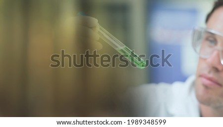 Composition of male scientist holding beaker test tube with copy space. science and research concept digitally generated image.