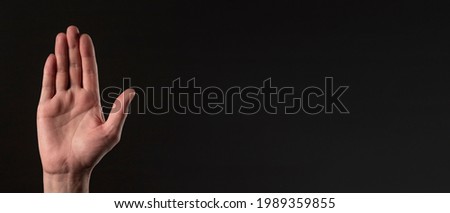 Male hand palm gesturing stop over black background. banner with copy space for text.