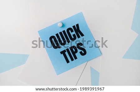 On a light blue background, white square sheets of paper. A light blue square sticker with the text QUICK TIPS is attached to them using a white paper clip.