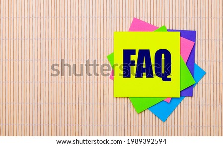 On a light wooden background, bright multicolored stickers with the text FAQ
