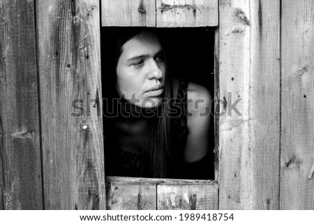 A young woman in a small window. Black-and-white photo.