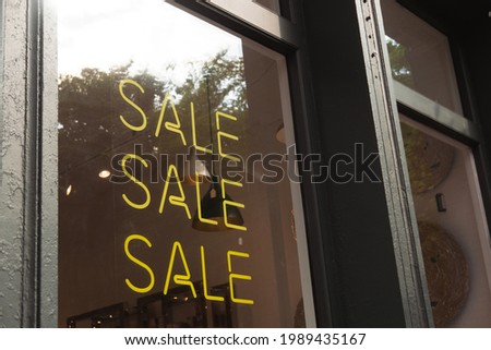 Stylish neon tube Sale sign on boutique window display, yellow color. Shopping, saving concept
