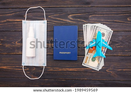 Top view photo of airplane, passport with dollars and medical poppies on wooden background. Travel concept.