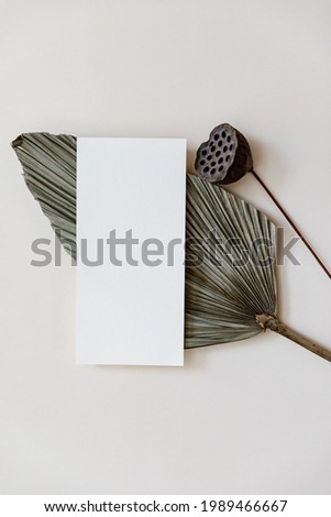 Minimal Summer stationery still life scene. Mock up with blank card and tropical palm leaf on beige neutral background. Blank greeting card, wedding invitation mockup scene 