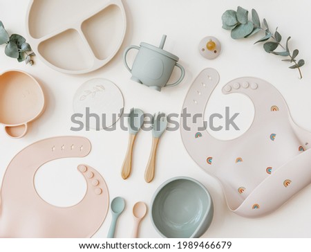 Flat lay Cute baby plate and Silicone bib with on neutral background. Top view, flat lay, baby serving first food Royalty-Free Stock Photo #1989466679
