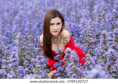 A woman long hair in red wear and margaret daisy garden background on hight hill, she is happy and like on trip for travel and take a photo