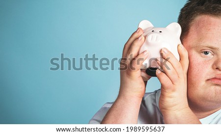 A young man with Down syndrome checking his piggy bank