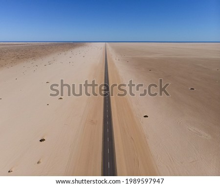 Aerial view of long and never ending street in Namibia. Drone photograph of straight road between sand. African landscape photography.