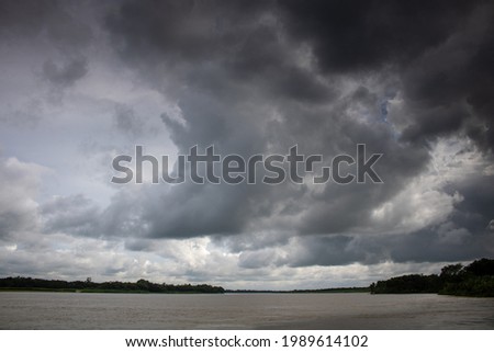 Cloudy skies. Thick black clouds on the chest of the river. The cloudy sky merged with the river.