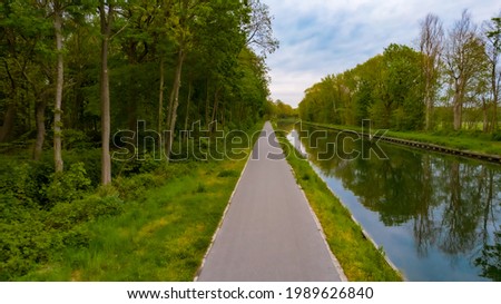 Beautiful view of Dessel-Schoten canal in Belgium. Pathway or Footpath along the water. Path passing by river. Sunny day. Landscape with path, trees, river. High quality photo