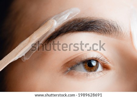 Closeup Master wax depilation of eyebrow hair in women, brow correction. Royalty-Free Stock Photo #1989628691