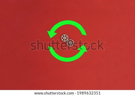 Two rounded green arrows, a pair of wooden gears on a red background. The concept of action, movement.